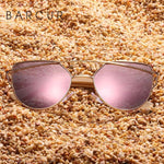 Pink cat eye sunglasses with bamboo arms on a beach